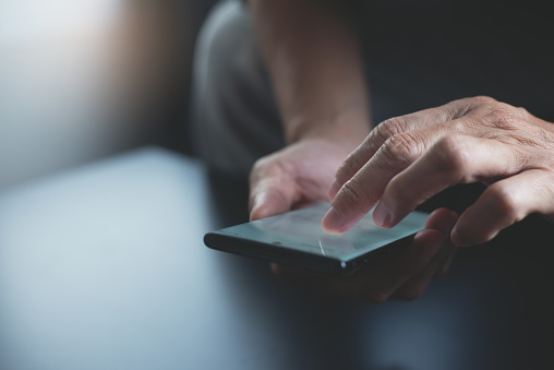 Close-up of man using mobile phone for searching information on internet.